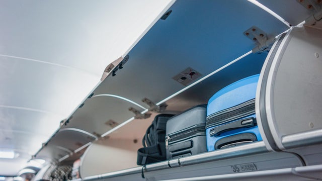 Overhead locker on airplane,Passenger put cabin bag cabin on the top shelf. Travel concept 