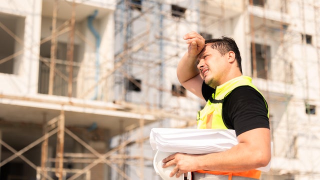 Tired Sweating Construction Worker On Building Site Under Sunlight 
