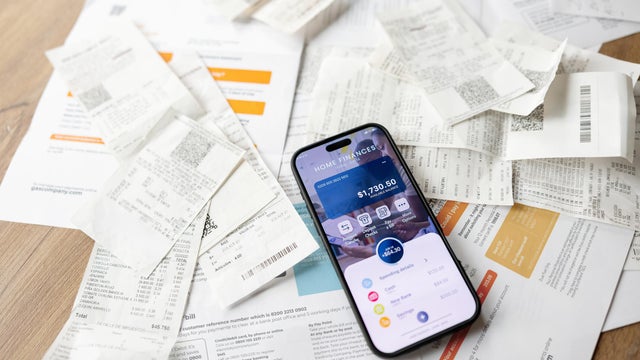 Electronic banking app open in a smart phone while it lies on top of invoices 