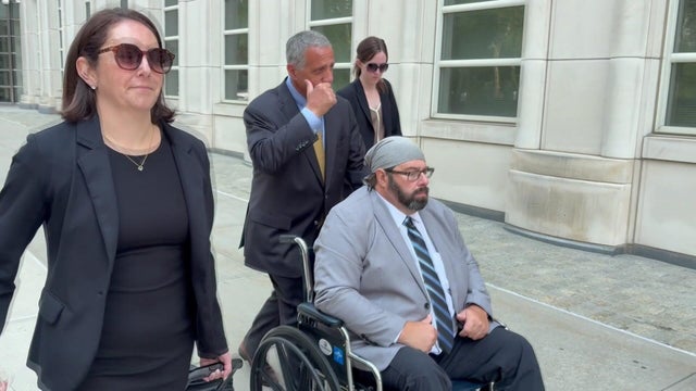 John Merrone being pushed in a wheelchair 
