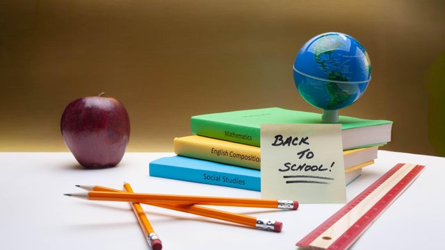 Back to School Books, Pencils and Globe with Apple and Ruler on Blue Background 