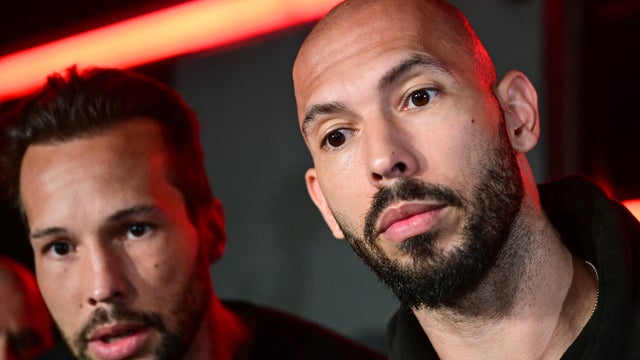 Andrew Tate, right, and his brother Tristan speak to the media as they arrive in Bucharest, Romania, March 22, 2025. 