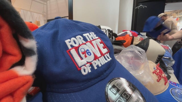 A blue Sixers hat that says For the Love of Philly on a pile of merch 