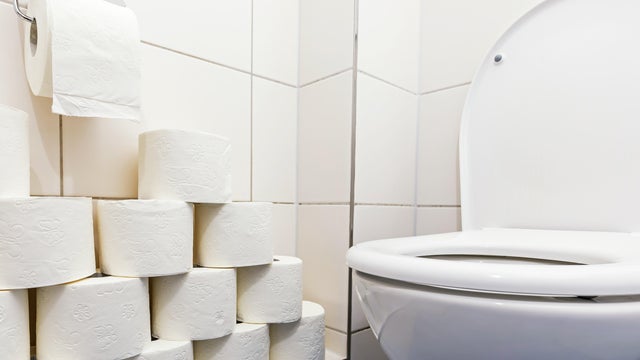 Toilet bowl with many rolls of toilet paper 
