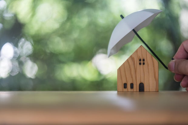 Home and real estate insurance ideas, Man use white small umbrellas and wood homes. 