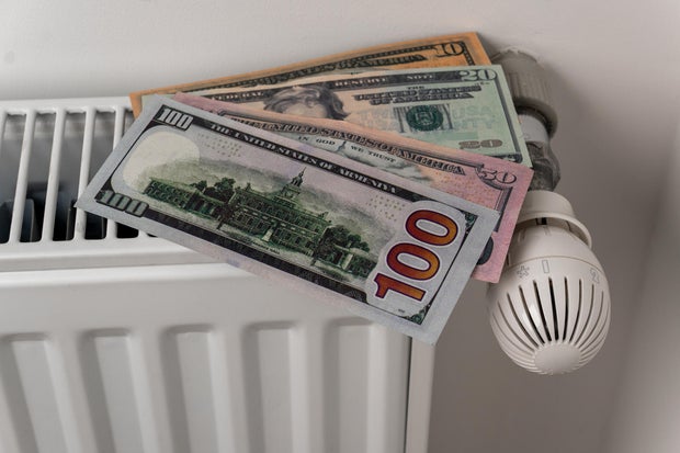 US dollar banknotes on central heating radiator with thermostat valve 