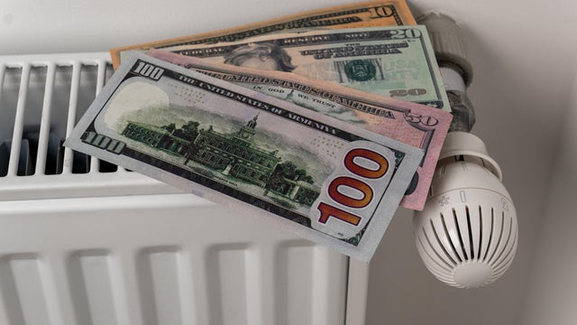 US dollar banknotes on central heating radiator with thermostat valve 