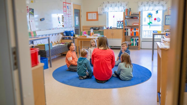 Teacher sitting on floor with children 