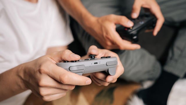Friends bonding and enjoying leisure time at home, deeply engaged in competitive console gaming session, using wireless controllers for interactive entertainment and digital fun 