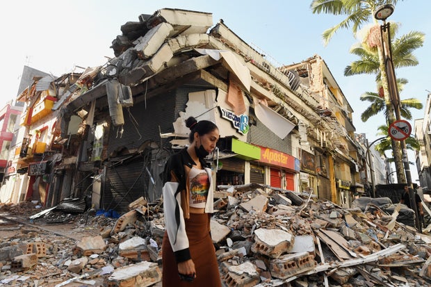 A woman walks past the rubble of a collapsed building after an earthquake in Pereira, Colombia, Aug. 11, 2026.