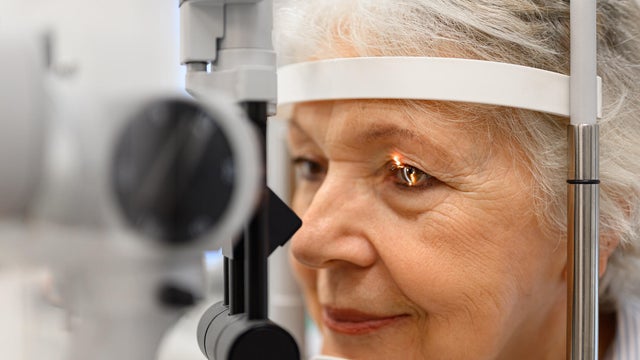 Close-up of mature patient undergoing detailed eye examination with slit lamp and light at ophthalmology clinic 
