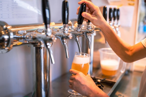 Female owner and young male brewer brewing beer in a microbrewery. 