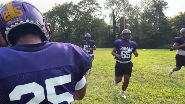 High school football players from Roman Catholic practice, their jerseys are purple 