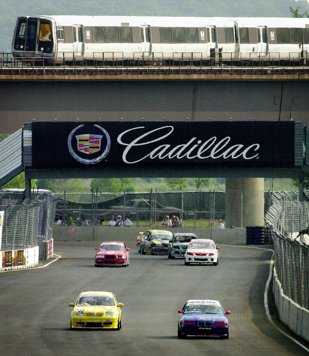 A Metro train passes above as race cars practice outside RFK Stadium on July 19, 2002, in preparation for the Cadillac Grand Prix in Washington. 