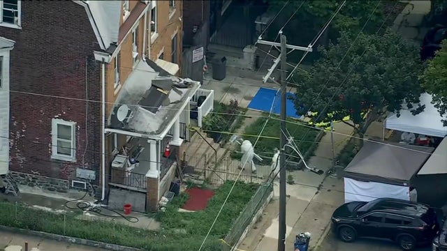 Drone image of two people in hazmat-like suits heading in to the house on West Chew Avenue in Olney that is under investigation 