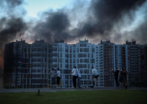 People look at smoke rising during a Russian drone strike in Kyiv, Ukraine, Aug. 20, 2026. 