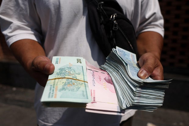 A currency dealer holds Iranian Rial in the Grand Bazaar in Tehran