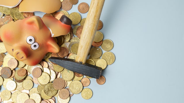 Breaking piggy bank with hammer extracting money 