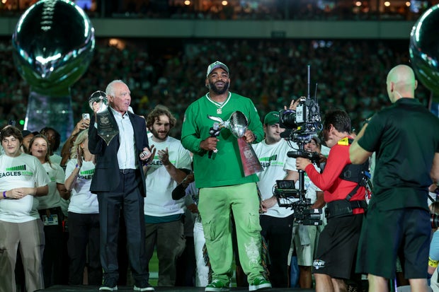 Jeffrey Lurie and Brandon Graham celebrate on the field after the Eagles hoisted the Super Bowl LIX banner at Lincoln Financial Field 