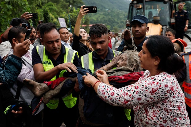 Police officers carry a survivor to a safer place following a flash flood at Trishuli, Nepal