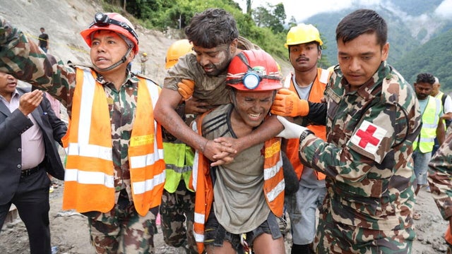 A man who survived is carried by members of a search and rescue team after being rescued from inside a tunnel at the Trishuli-3A Hydropower Project following devastating floods and mudslides that struck the Bhotekoshi River 