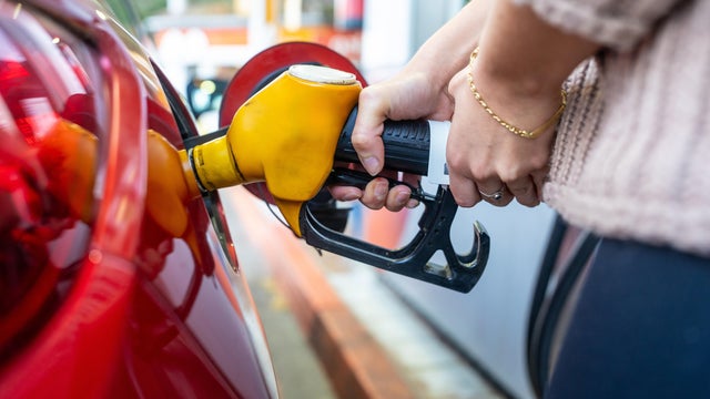Person filling car with gasoline at gas station 
