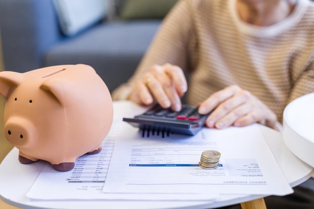 Person calculating finances with piggy bank and coins