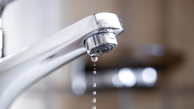 Dripping tap with water droplets inside apartment bathroom. Macro, close up, looking up shot, shallow depth of field, no people 