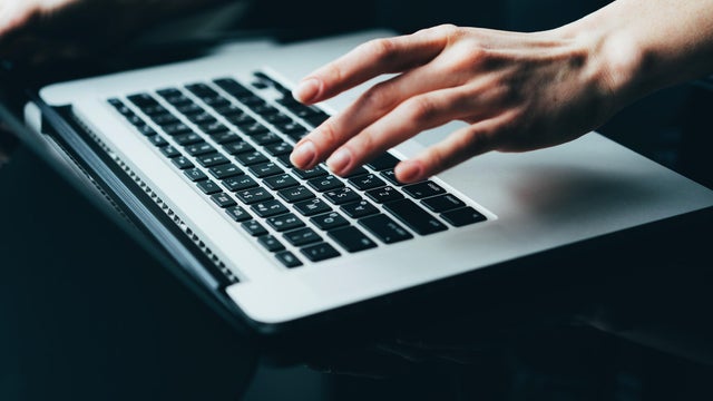 Close-Up of Hand Typing on a Modern Laptop Keyboard in Dark Lighting 