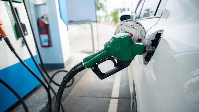 Transport and industry concept. Refilling the car. A refueling valve is inserted into the fuel filler neck. White car at gas station being filled with fuel 