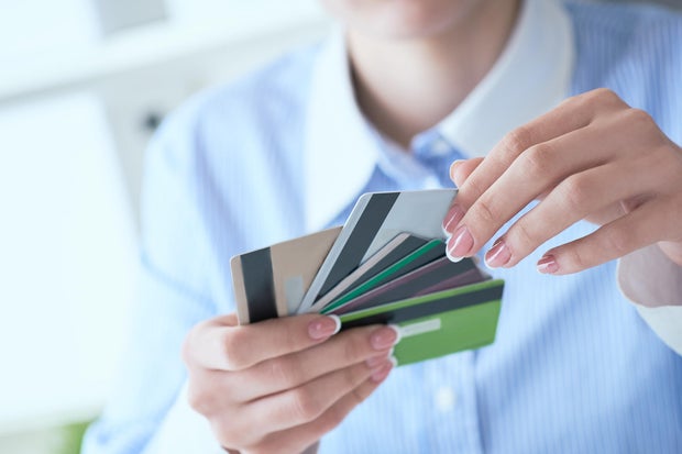 Woman hand holding various credit cards and making choice with another hand close-up.