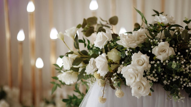 The wedding reception hall is decorated with fresh white roses 