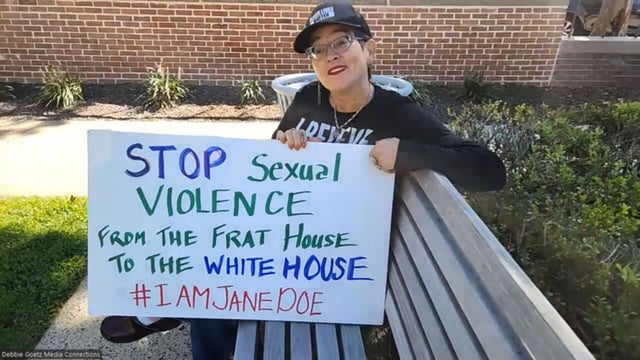 Marlene Pray holds a sign that says Stop sexual violence from the frat house to the White House, hashtag I am Jane Doe 