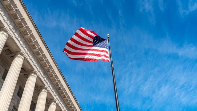 American flag flapping boldly in the wind with The Supreme Court in Washington DC, USA. 
