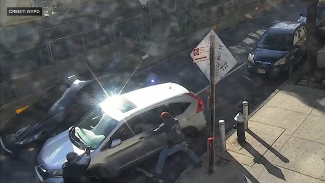 Two ICE agents pointing guns at a driver inside a vehicle 
