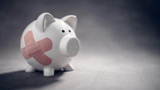 Broken piggy bank with band aid bandage or plaster finance background 