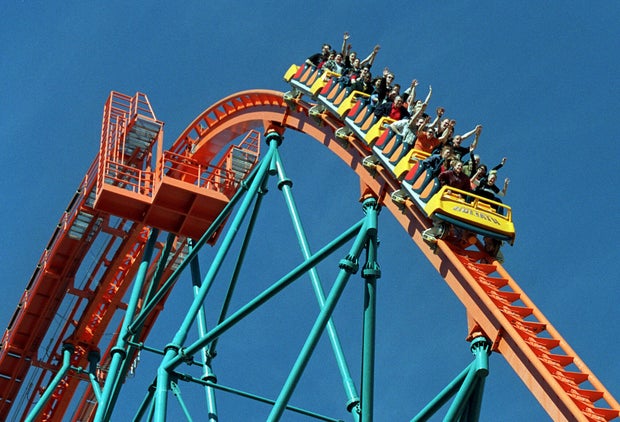Roller coaster riders throw their hands in the air as they ride 