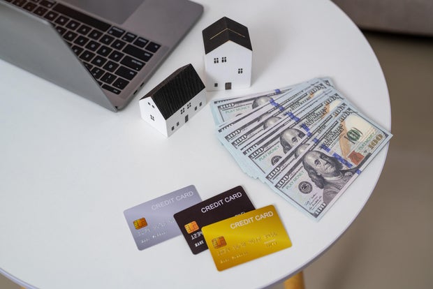 Small house with the dollar bills, credit card and transparent clock background. concept of the home payment interest of house loan monthly installment. Finance and Real Estate Investment. 