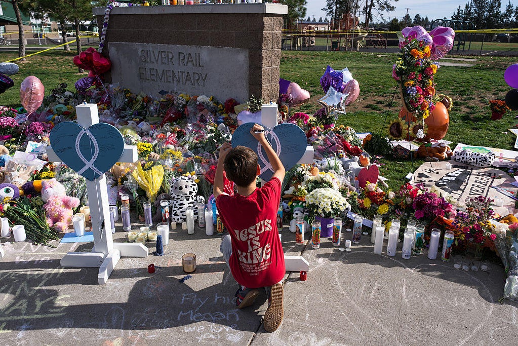 A child writes a message on a cross at a memorial at Silver Rail Elementary School in Bend, Oregon, Oct. 17, 2026. Cody Rheault/The Washington Post via Getty Images